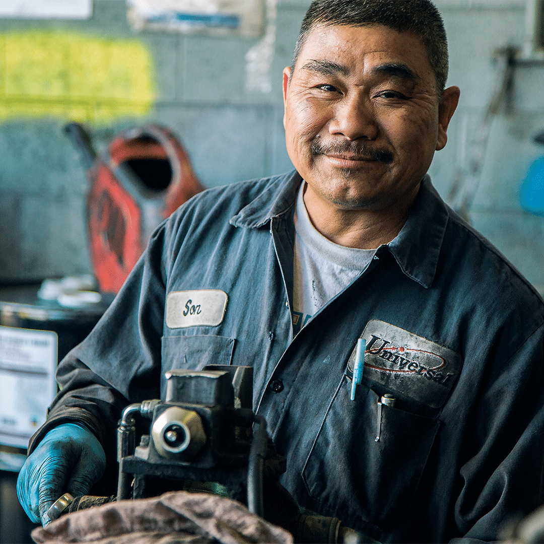 A photograph of a Universal worker, working on car parts.